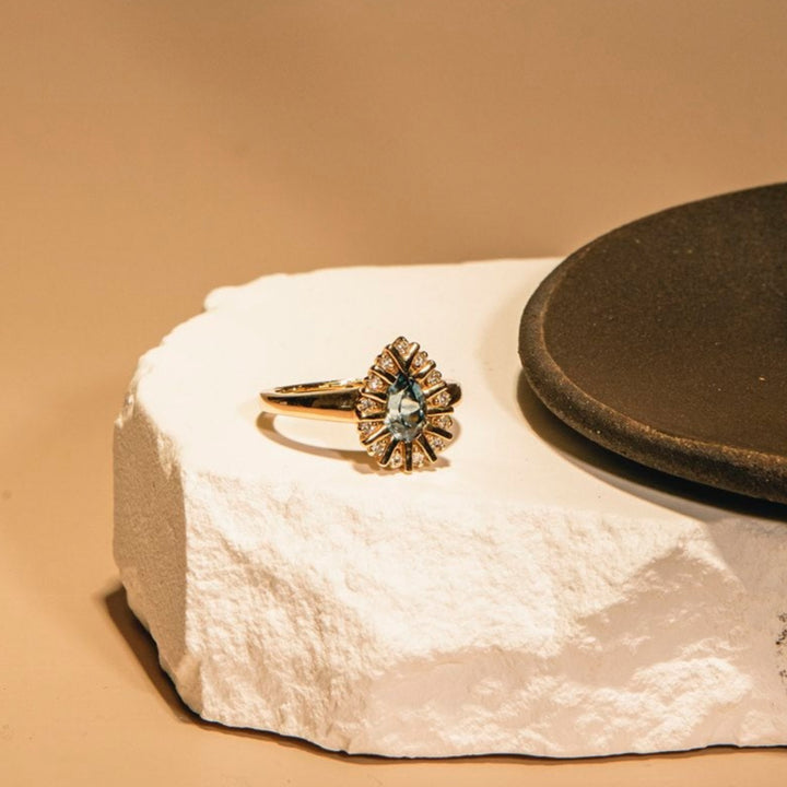 Gold ring with a star-like design on a textured white surface with a brown background