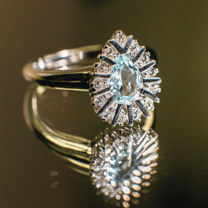 Silver ring with a central gemstone on a reflective surface