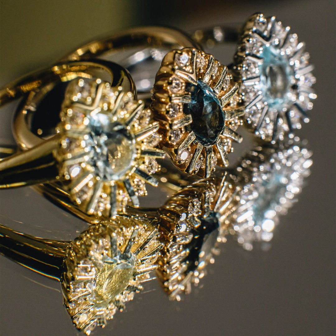 Close-up of gold rings with gemstones on a reflective surface