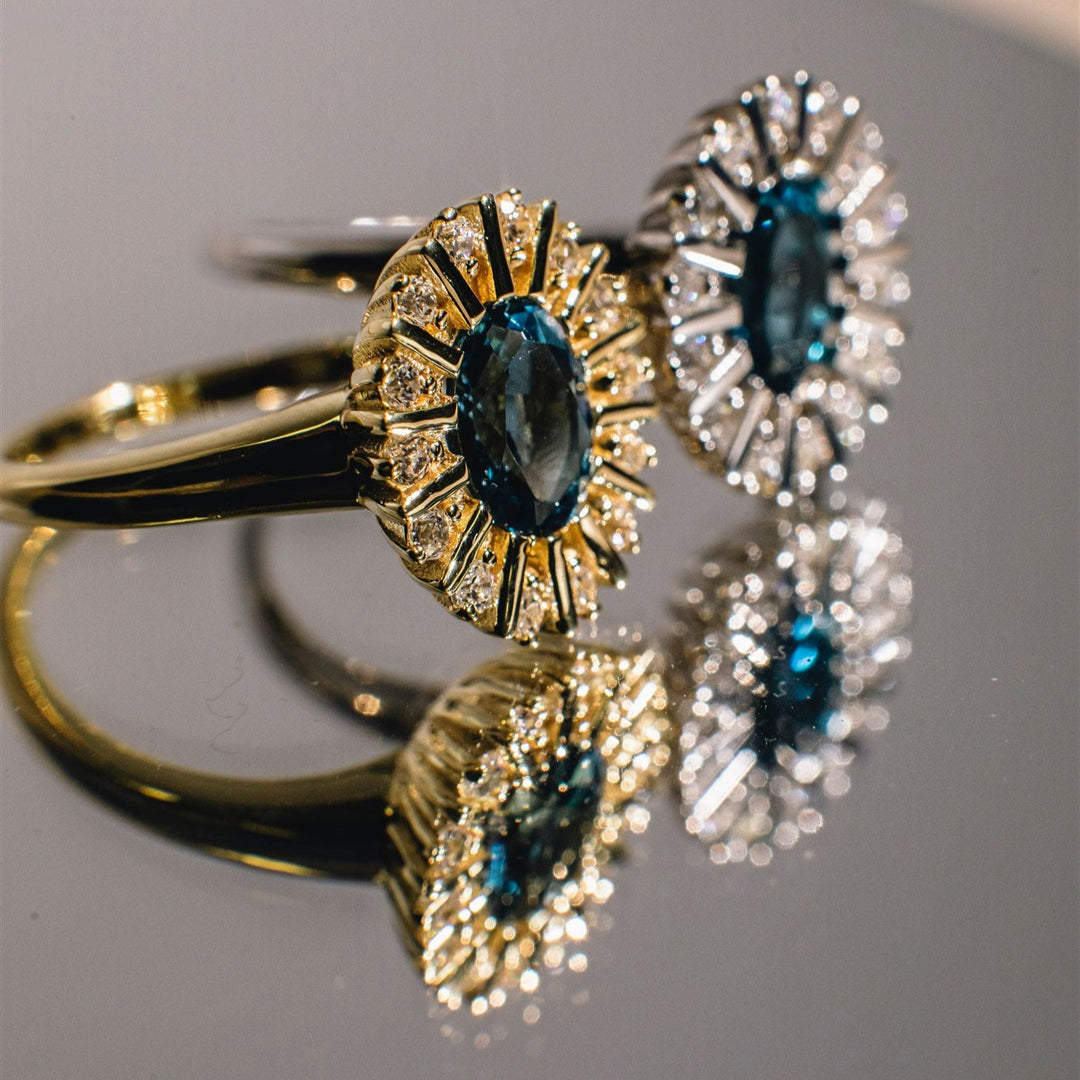 Close-up of gold and silver rings with gemstones on a reflective surface