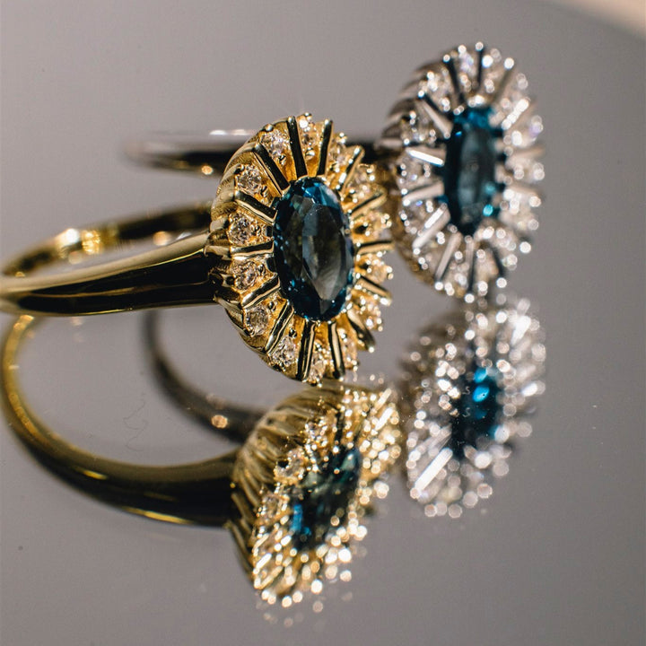Close-up of gold and silver rings with gemstones on a reflective surface