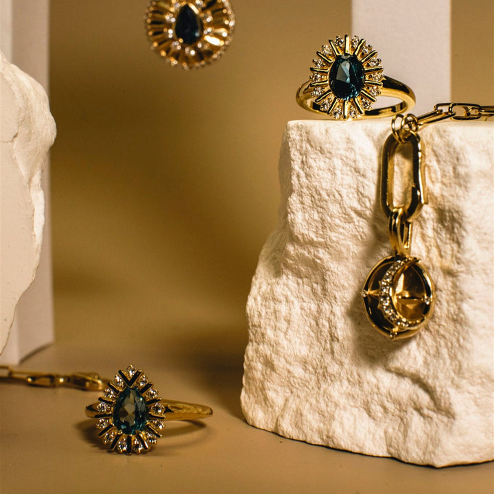 Gold jewelry set with rings and a necklace on a textured white surface.