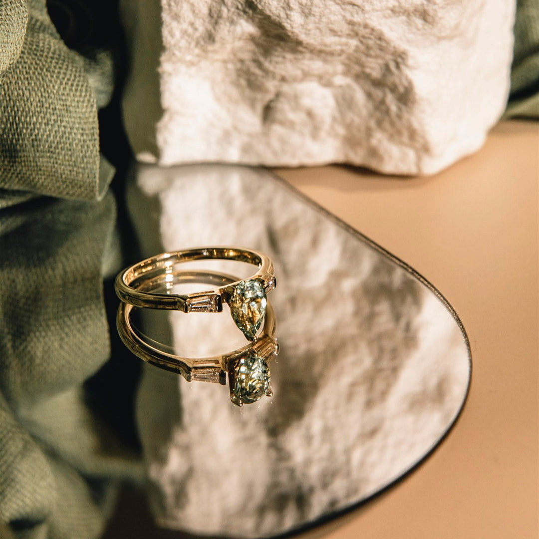 Gold ring with a green gemstone on a textured surface