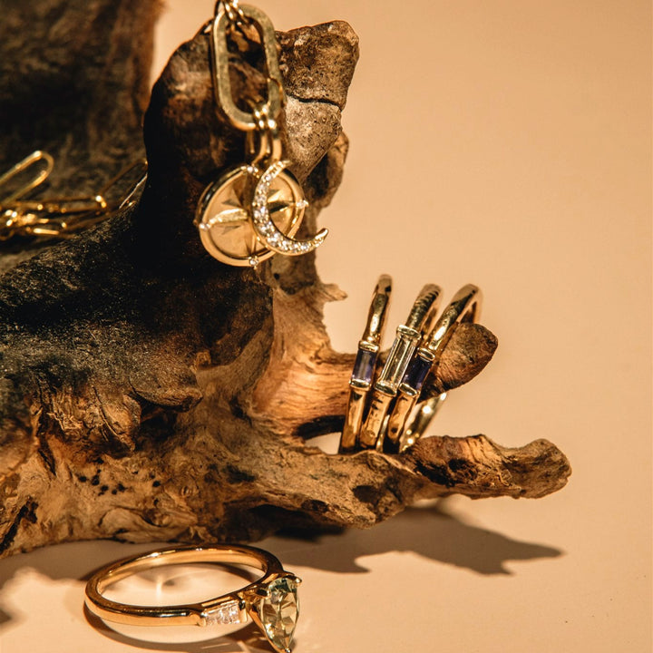 Gold jewelry including rings and earrings on a textured surface