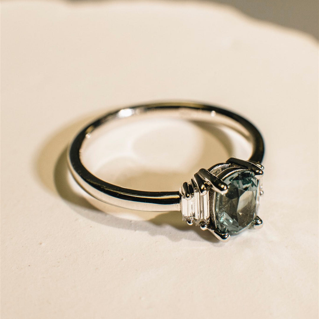 Gold ring with a green gemstone on a beige background