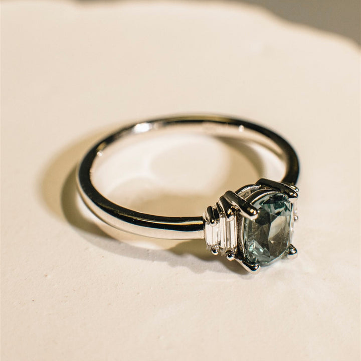 Gold ring with a green gemstone on a beige background