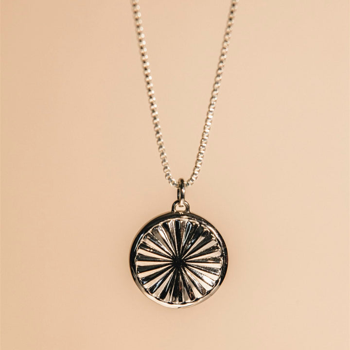 Silver necklace with a round pendant on a beige background