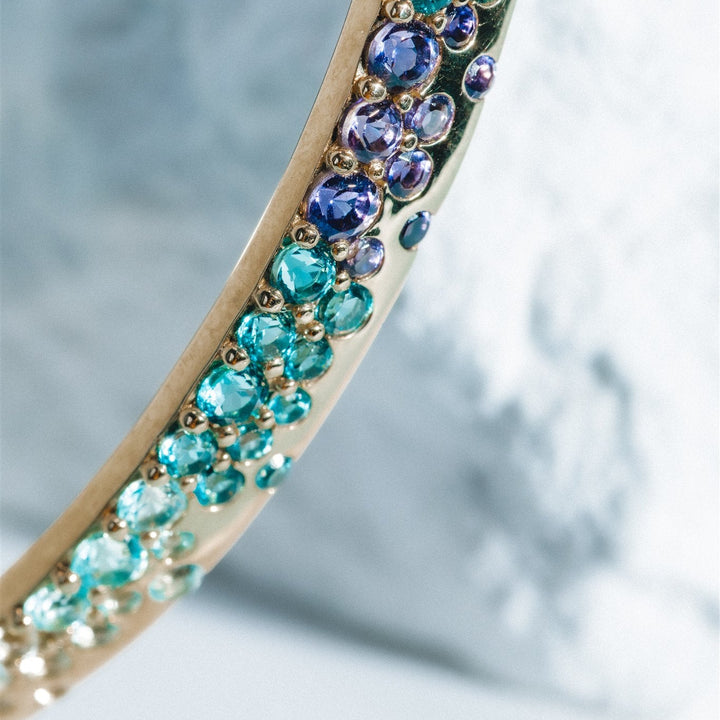 Close-up of a bracelet with turquoise and purple gemstones on a light background