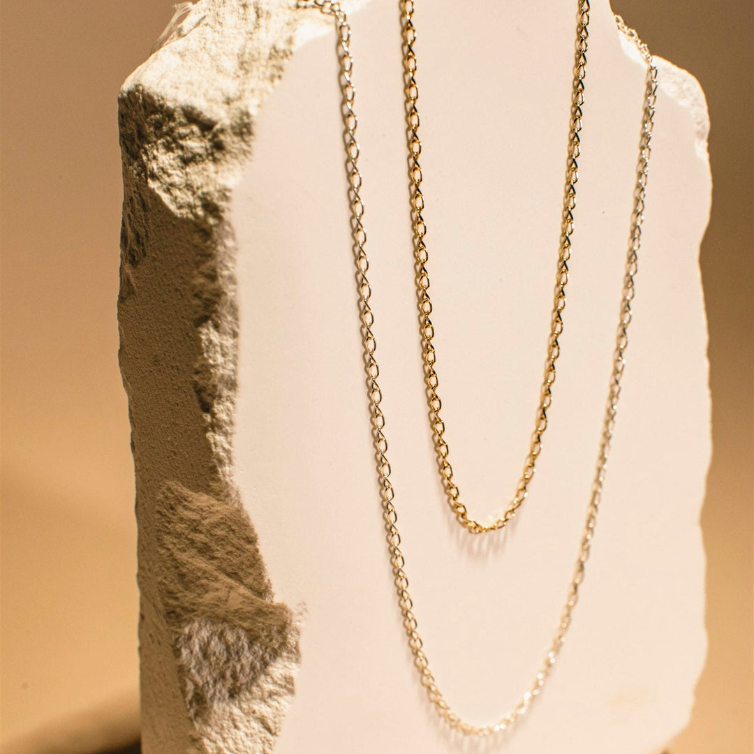 Gold chain necklace on a mannequin bust with a neutral background