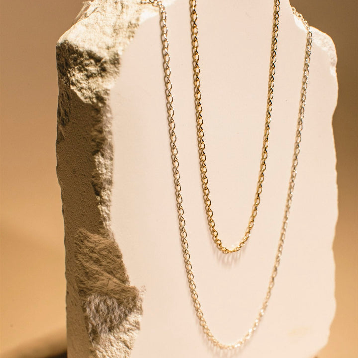 Gold chain necklace on a mannequin bust with a neutral background