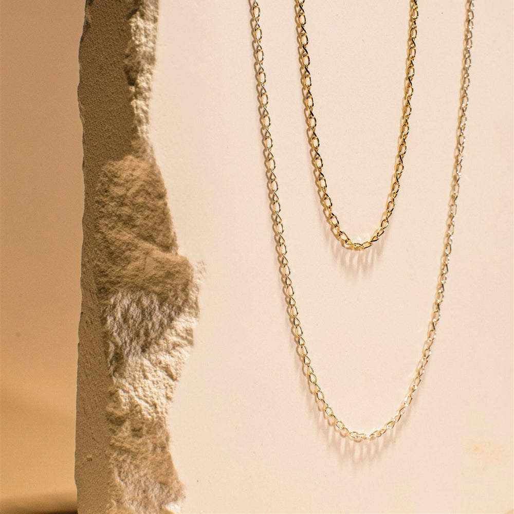 Gold chain necklace on a textured stone surface