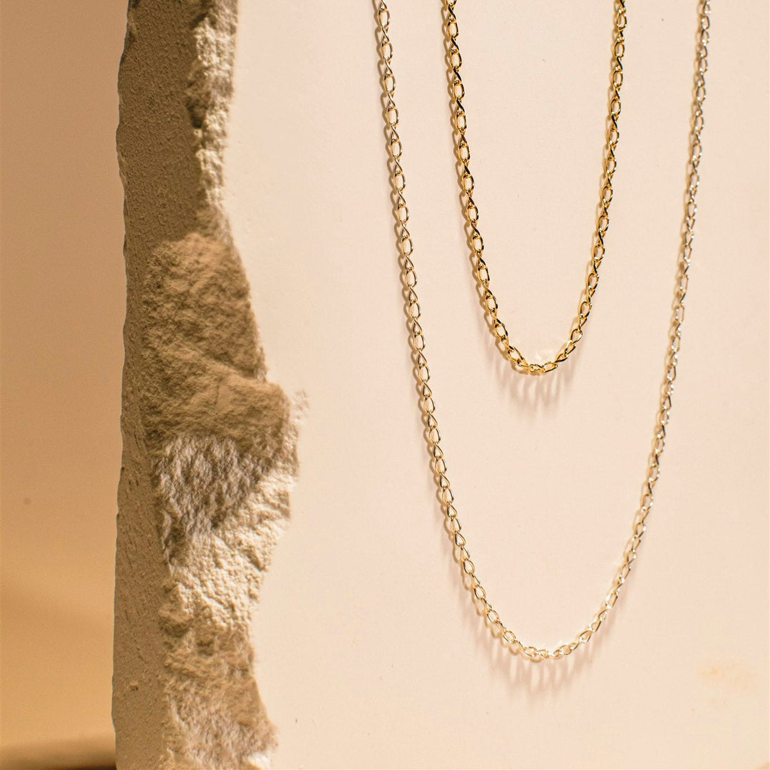 Gold chain necklace on a textured stone surface