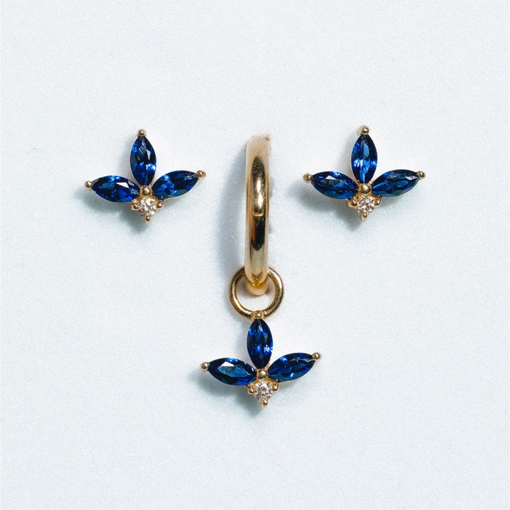 Gold earrings with blue gemstones on a white background