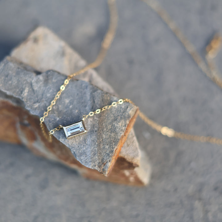 Gold necklace with a pendant on a rough stone surface