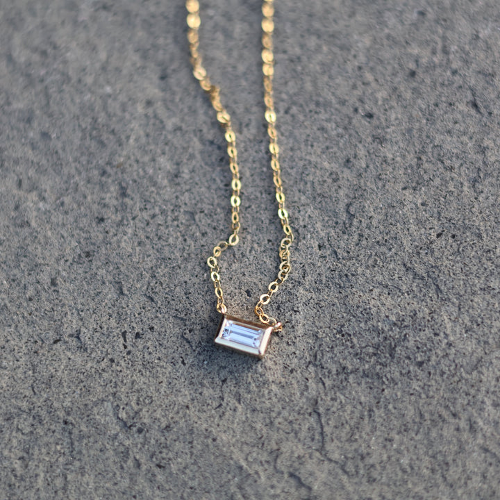 Gold necklace with a pendant on a textured gray surface
