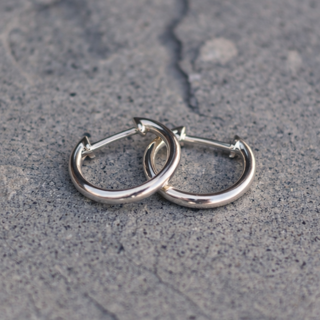 Pair of silver hoop earrings on a textured gray surface