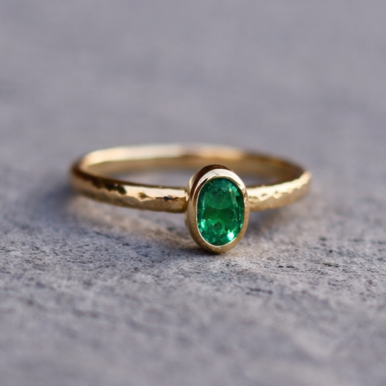 Gold ring with a green gemstone on a textured gray surface