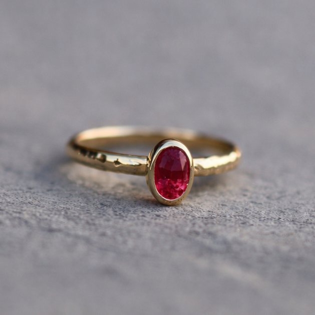 Gold ring with a red gemstone on a gray surface