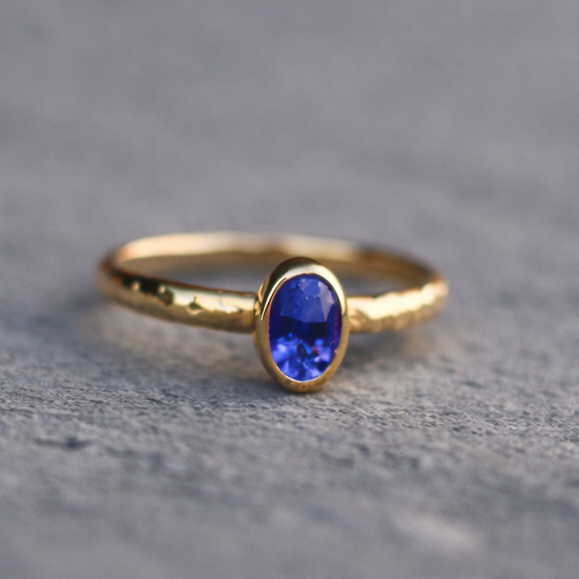 Gold ring with a blue gemstone on a gray surface