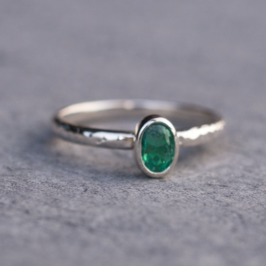 Silver ring with a green gemstone on a gray surface