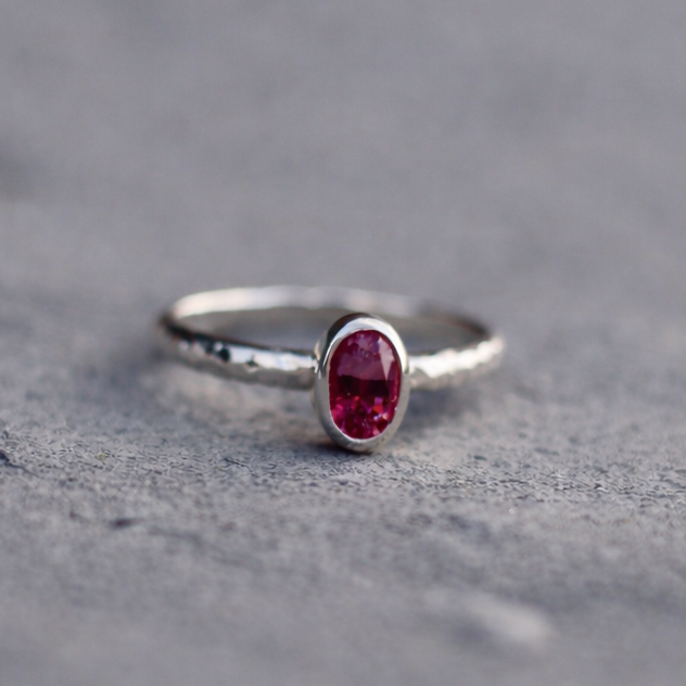 Silver ring with a red gemstone on a gray surface