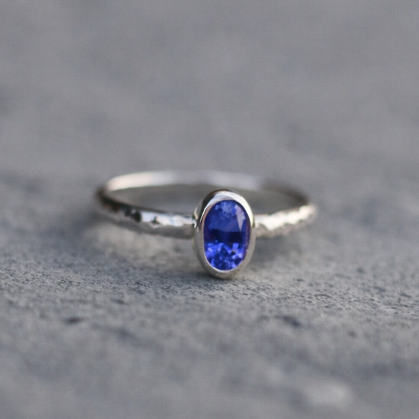 Silver ring with a blue gemstone on a gray surface