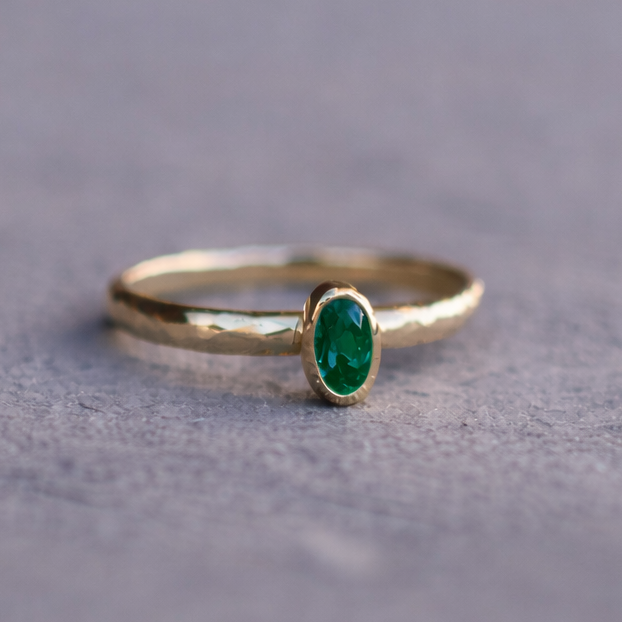 Gold ring with a green gemstone on a gray surface