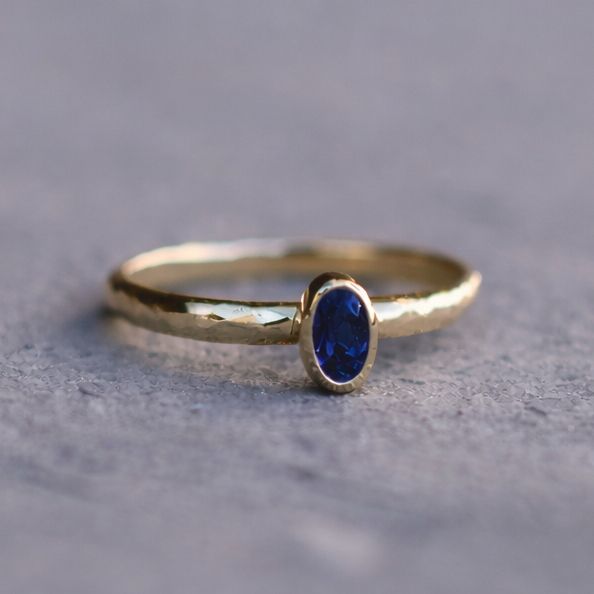 Gold ring with a blue gemstone on a textured gray surface