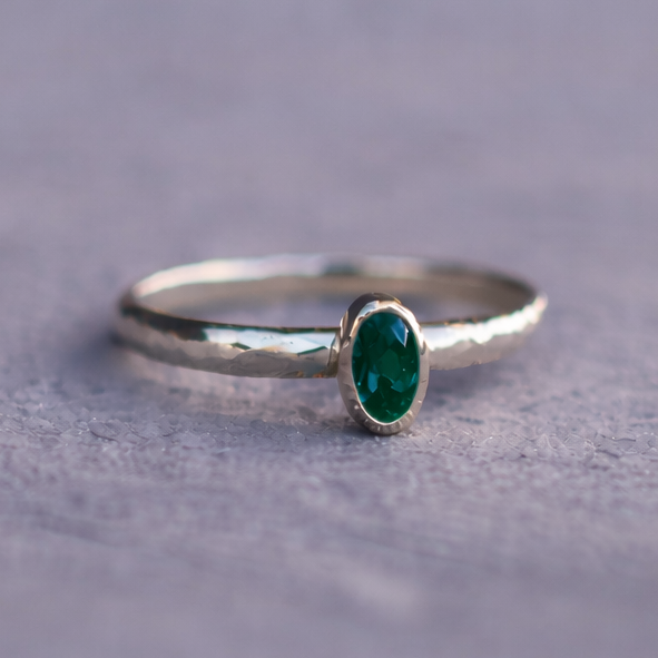 Silver ring with a green gemstone on a gray surface