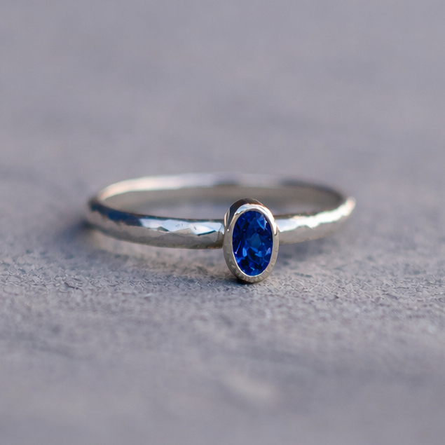 Silver ring with a blue gemstone on a gray surface