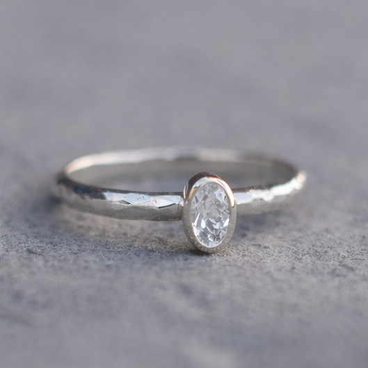 Silver ring with a white sapphire on a gray surface