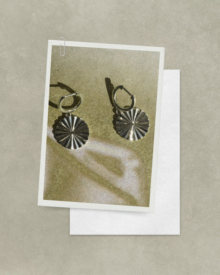 Fluted gold Sol coin huggies on a postcard