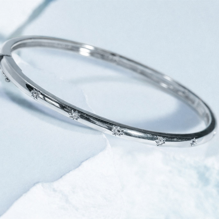 Silver bracelet with small stones on a light blue background