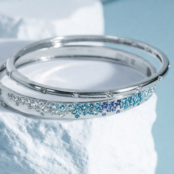 Silver bracelet with blue gemstones on a white fabric background