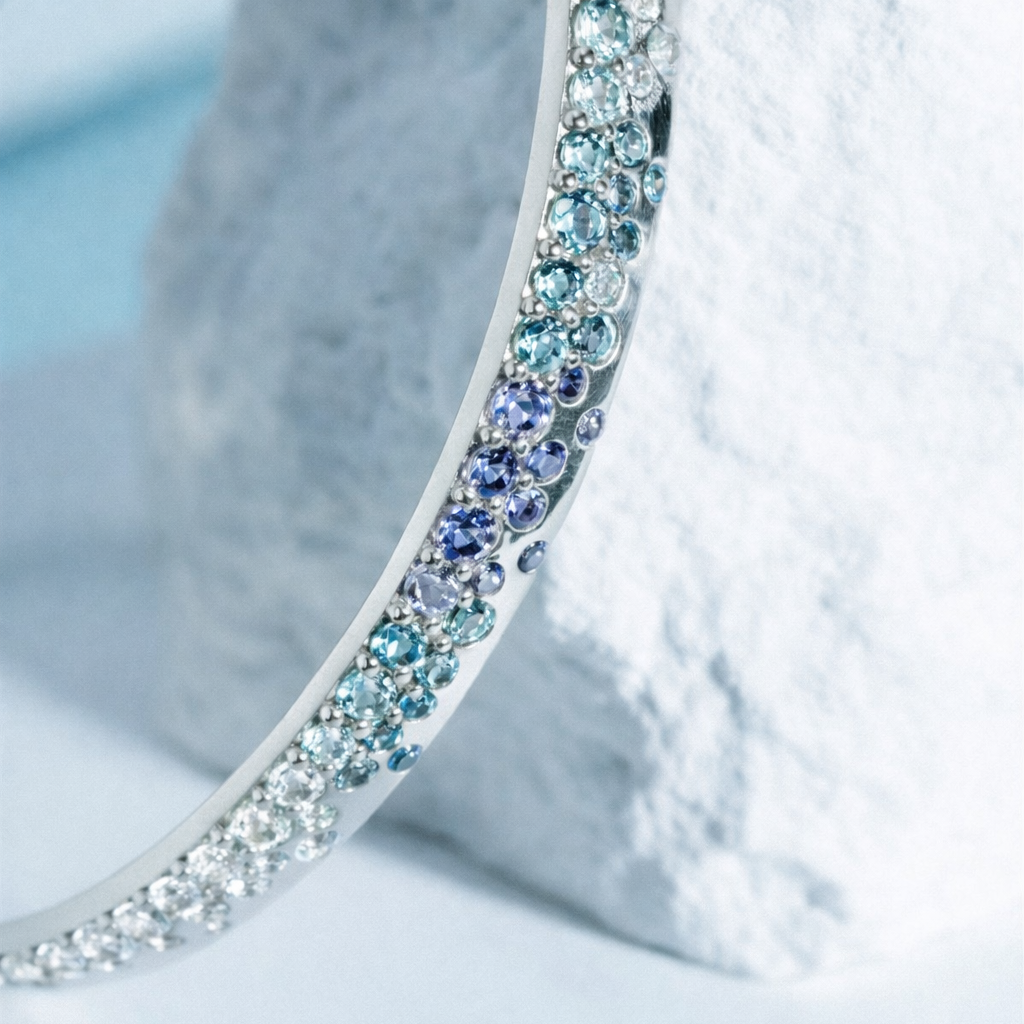Close-up of a silver bangle with multicolored stones on a textured white surface.