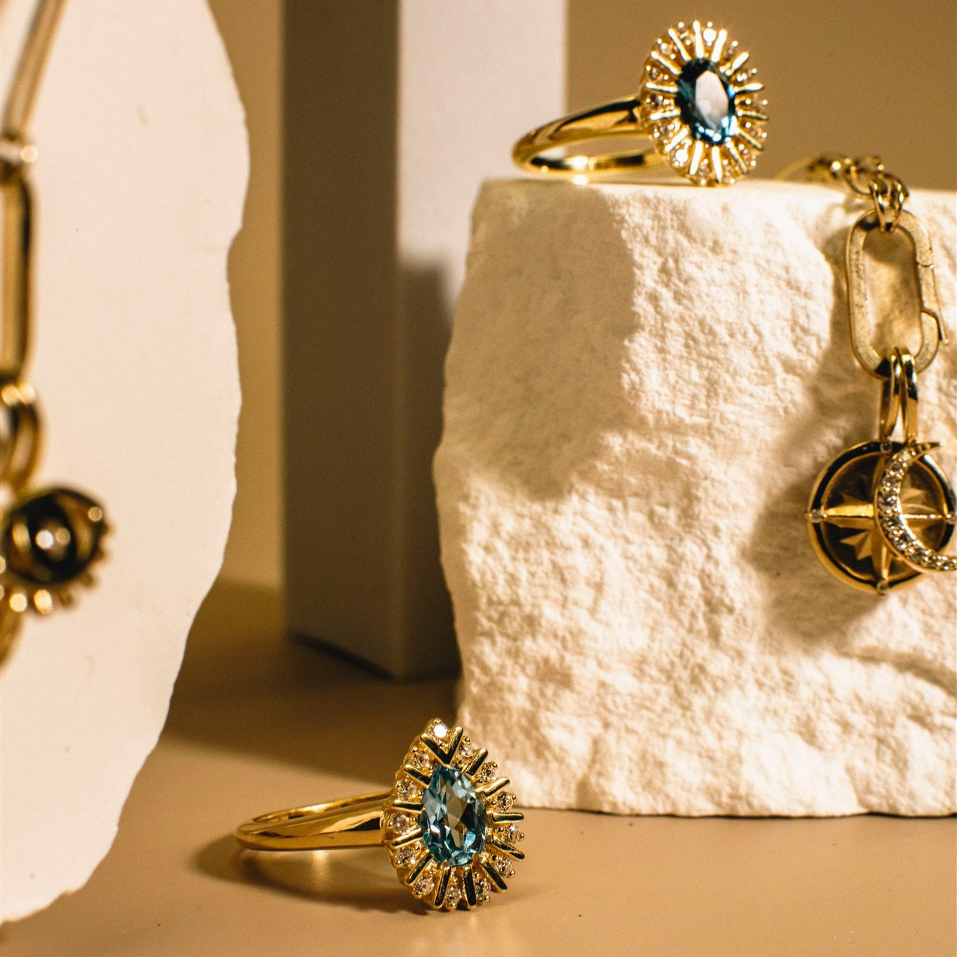 Headwaters rings in gold with blue gemstones, arranged on a textured white surface — Talismania