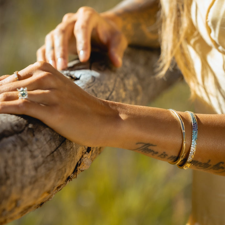 Hands wearing Talismania gold jewelry outdoors — Talismania
