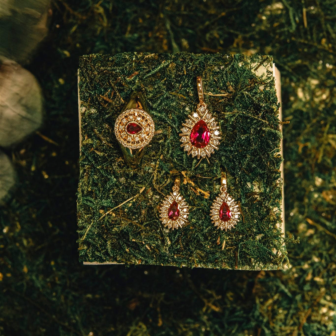 Jewelry set with red gemstones on a textured green surface