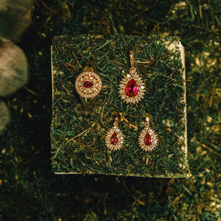 Jewelry set with red gemstones on a textured green surface